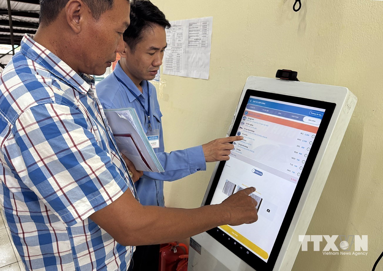 Nhân viên Ban Quản lý cảng cá Hòn Rớ hướng dẫn ngư dân thực hiện khai báo điện tử sản lượng thủy sản tại cảng cá nhanh chóng bằng cách sử dụng ứng dụng eCDT VN. (Ảnh: Vũ Sinh/TTXVN)